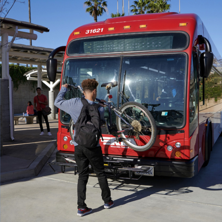 Student loading bicycle onto a bus